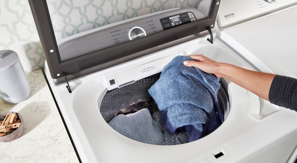 Clothing being handled at a top-loading washer in the source laundry-sorting guide.