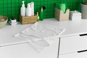 A light-colored sweater laid across a counter beside a sink in the source cashmere-care guide.