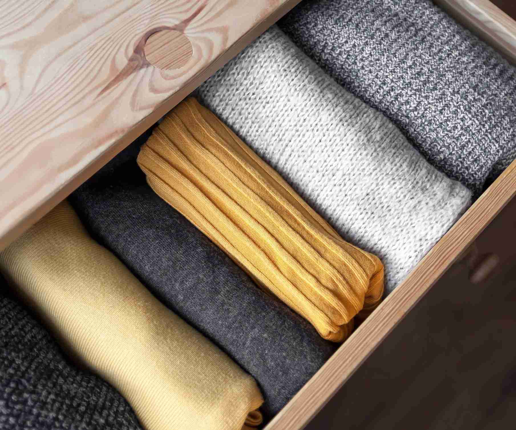 Folded knitwear arranged in a drawer in the source winter-clothing storage guide.