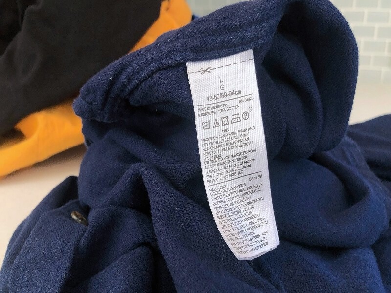 A garment care label sewn into navy fabric in the source sorting guide.
