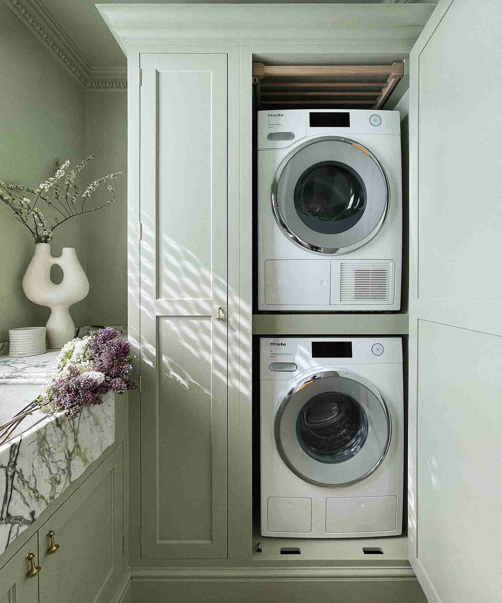A stacked washer and dryer fitted into cabinetry in the source laundry-organization article.