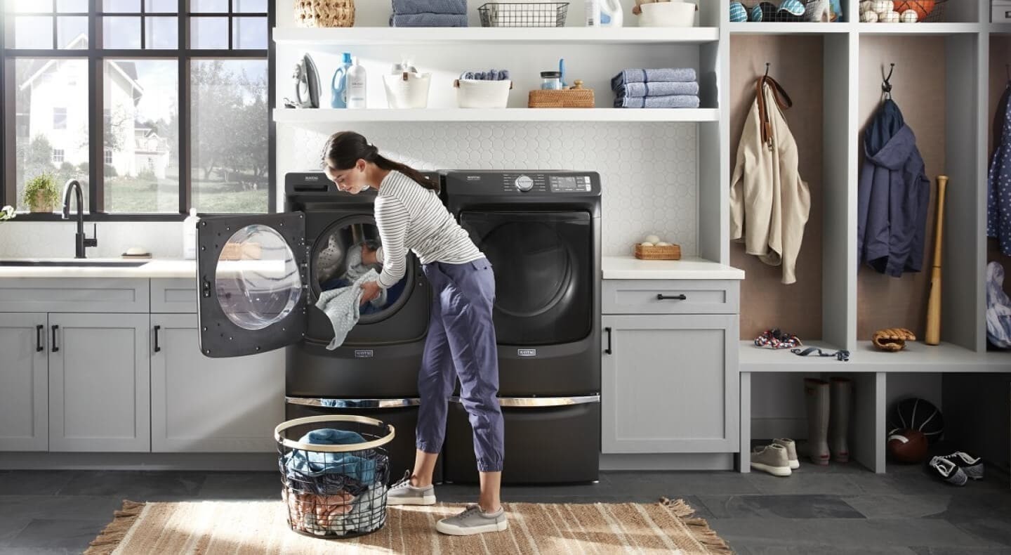 A person loading a front-loading washer in the source mud-and-dirt guide.