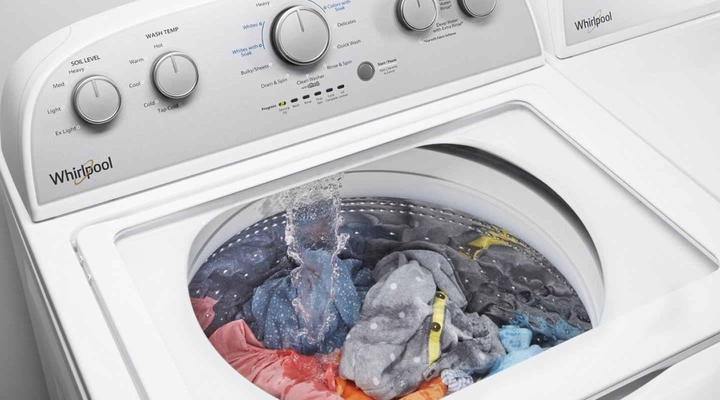 Water entering a top-loading washer containing laundry in the source makeup-removal guide.