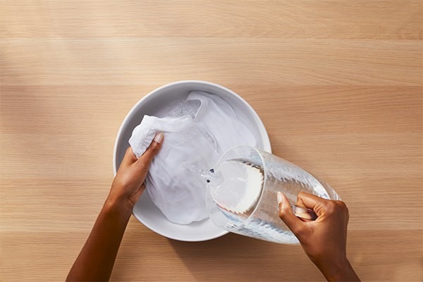 A white garment being rinsed in a basin in the source collar-and-cuff guide.