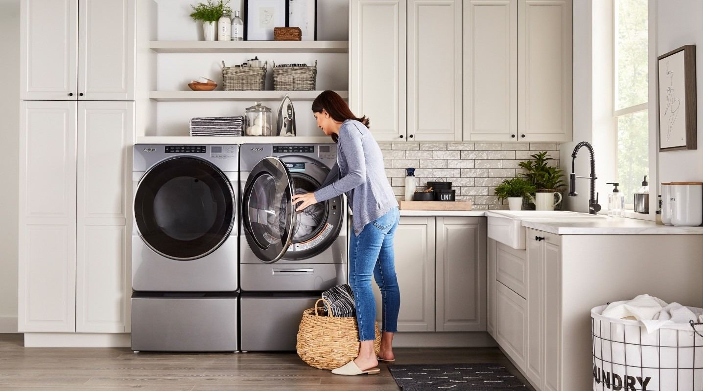A person handling laundry at a front-loading appliance in the source underarm-stain guide.