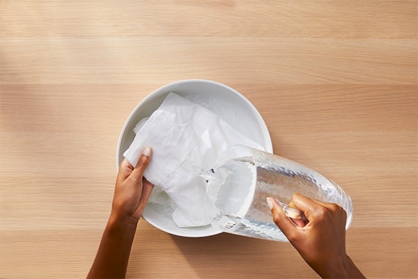 Water being poured over a white textile in a basin in the source cooking-oil guide.